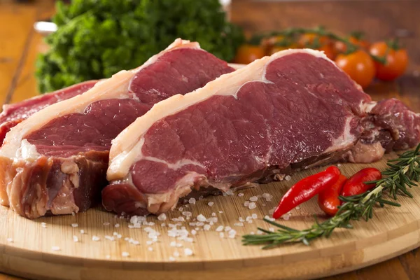Surowe mięso: wołowiny świeży filet z czosnkiem i zielone rzeczy na drewno — Zdjęcie stockowe