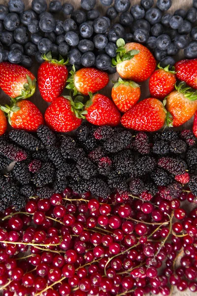 Einige rote Früchte über einem Holztisch. — Stockfoto