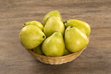 Ahşap bir yüzey üzerinde bir sepet içinde bazı armut