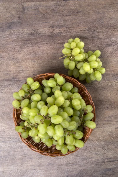 Raisins verts dans un panier sur une surface en bois . — Photo