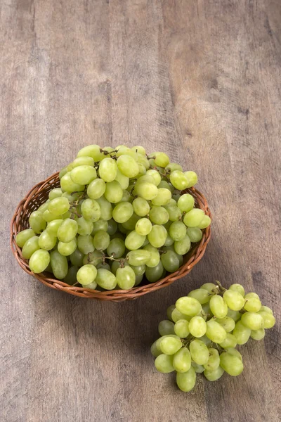 Zielony winogron w koszu na powierzchni drewnianych. — Zdjęcie stockowe
