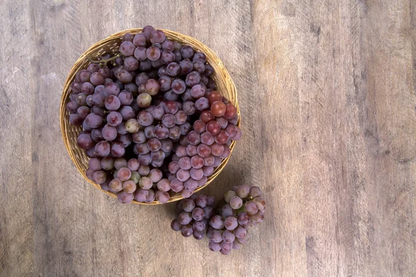 Quelques raisins rouges dans un pot en bois sur une surface en bois . — Photo