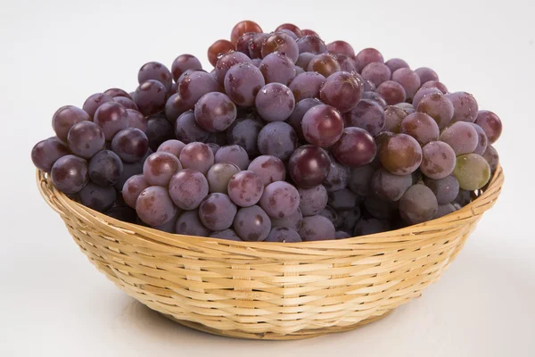 Немного красного винограда в деревянном горшке на белом фоне — стоковое фото