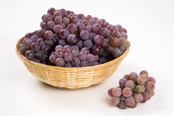 Some red grapes in a wooden pot over a white background — Stock Photo, Image