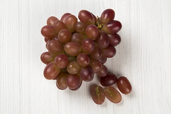 Unas uvas rojas sobre un fondo blanco — Foto de Stock