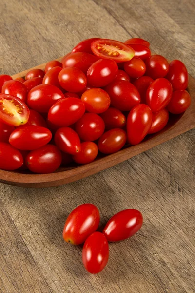 Een kom voor grape tomatoes over een houten tafel — Stockfoto