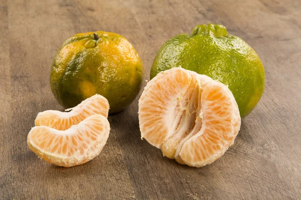 Algunas mandarinas en una canasta sobre una superficie de madera — Foto de Stock