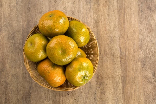 Některé mandarinky v košíku dřevěného povrchu — Stock fotografie