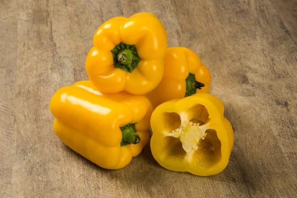 Some yellow peppers over a wooden surface — Stock Photo, Image