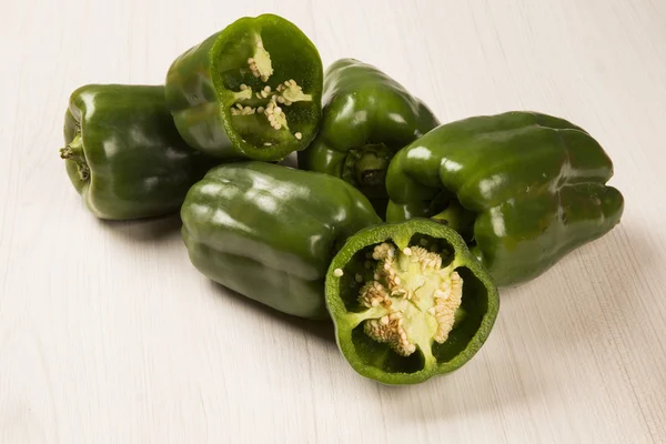 Sommige groene paprika's over een houten oppervlak. — Stockfoto