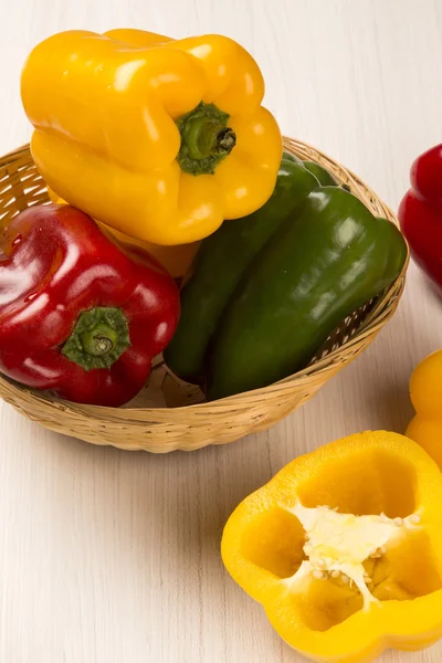 Algunos pimientos rojos, verdes y amarillos sobre una superficie de madera — Foto de Stock