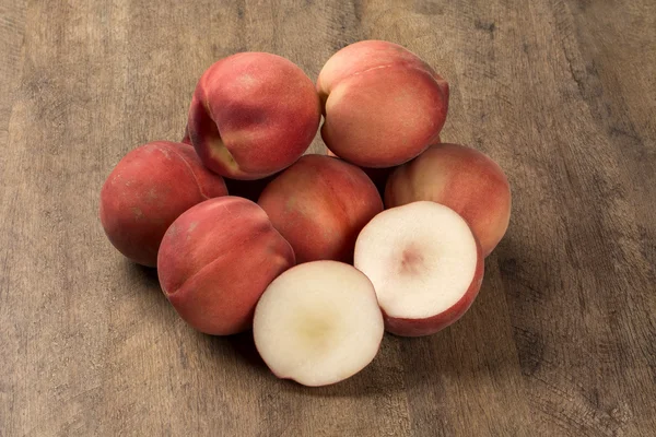 Some peaches in a basket over a wooden surface — Stock Photo, Image