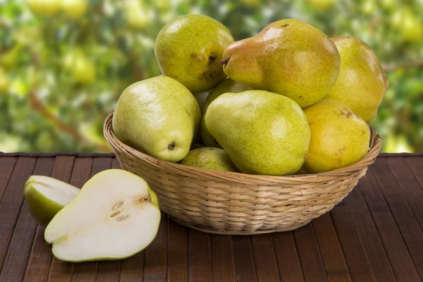 Sommige peren in een mand over een houten oppervlak — Stockfoto