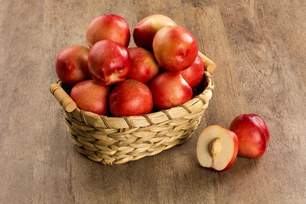 Персики в корзине над деревянной поверхностью . — стоковое фото