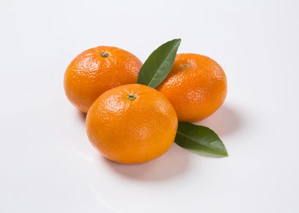Algunas mandarinas en una canasta sobre un fondo blanco . — Foto de Stock