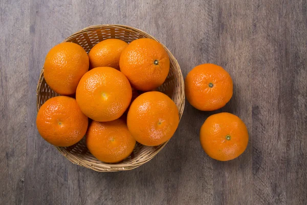 Algunas mandarinas en una canasta sobre una superficie de madera — Foto de Stock