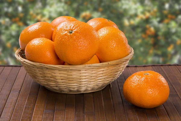 Algunas mandarinas en una canasta sobre una superficie de madera — Foto de Stock