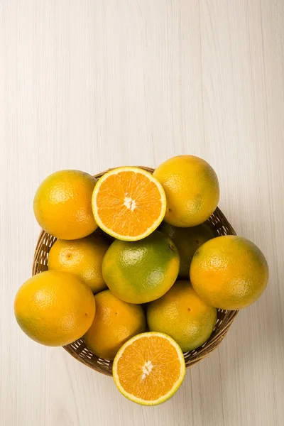 Close up of some oranges in a basket over a wooden surface — Stock Photo, Image