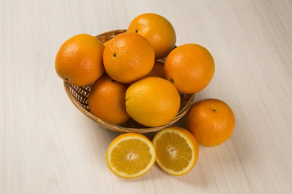 Close up de algumas laranjas em uma cesta sobre um fundo branco . — Fotografia de Stock