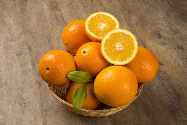 Nahaufnahme einiger Orangen in einem Korb über einer Holzoberfläche — Stockfoto