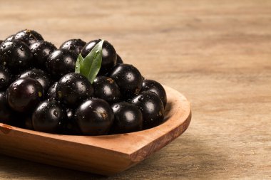 Berry Jaboticaba in bowl on wooden table clipart