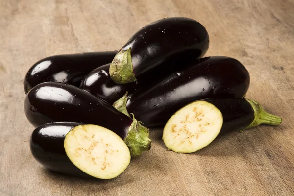 Sommige aubergines over een houten oppervlak — Stockfoto