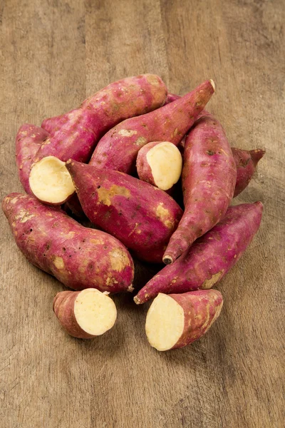 Rohe Süßkartoffeln auf hölzernem Hintergrund — Stockfoto