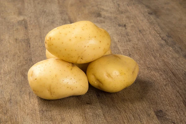 Algumas batatas sobre uma superfície de madeira — Fotografia de Stock