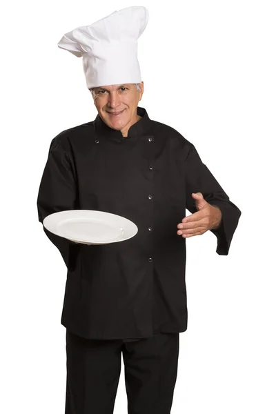Vertrouwen volwassen chef-kok in zwarte uniform houden lege plaat. — Stockfoto