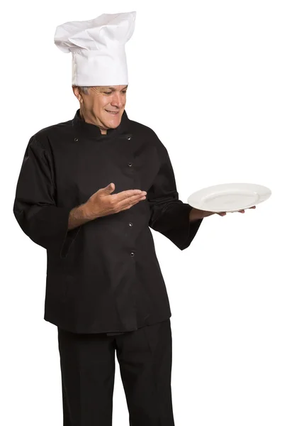Säker mogna kock i svart uniform håller Tom tallrik. — Stockfoto