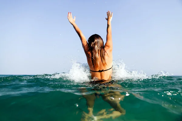 Sexy girl swim sea waves hands up splash back view — Stock Photo, Image