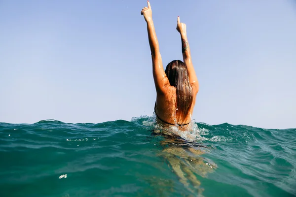 性感的女孩游泳海波浪举起手来溅后视图 — 图库照片