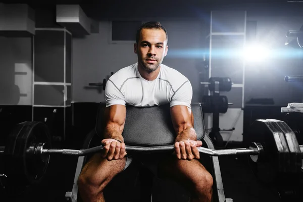 Handsome bodybuilder pumping up hands in gym — Stock Photo, Image