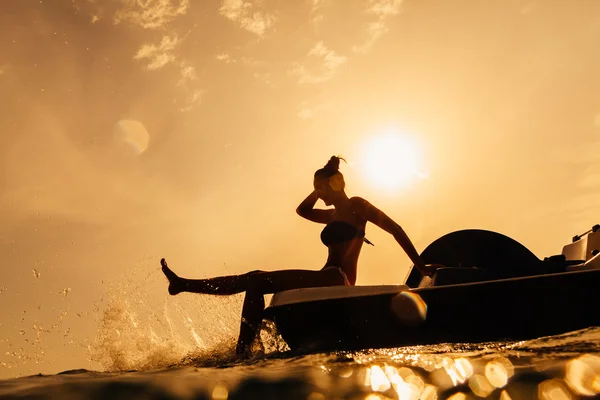 Menina em barco de remo com bokeh luz solar e respingo de água — Fotografia de Stock