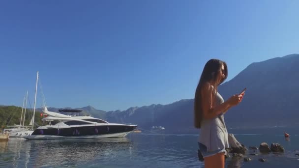 Dziewczyna Szukaj w smartfonie w malowniczej zatoce — Wideo stockowe
