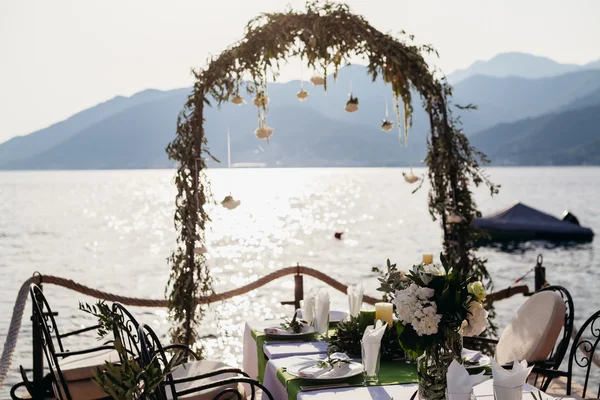 Destination bröllop arch och banqouet täcks bord vid solnedgången — Stockfoto