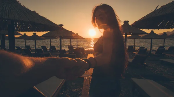 Man följa kvinnan på sunset beach — Stockfoto