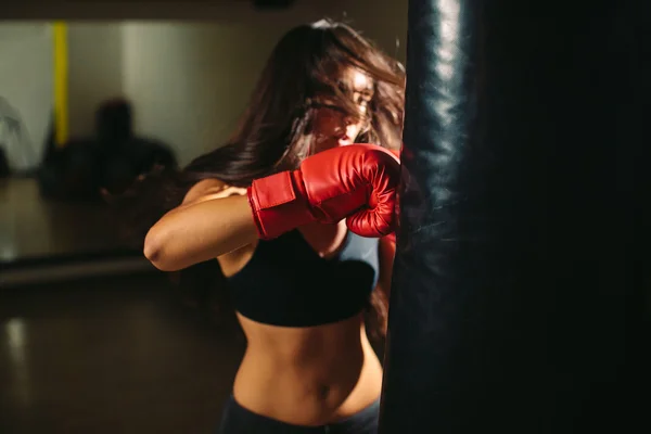 Fighter girl punching boxing bag — Stock Photo, Image