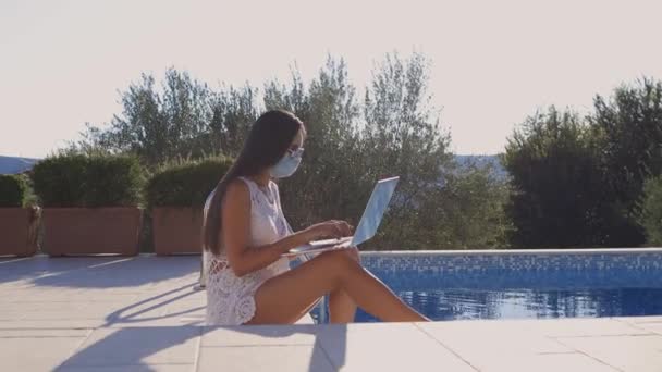 Frau mit Laptop aus der Ferne auf soziale Distanz mit Gesichtsmaske — Stockvideo