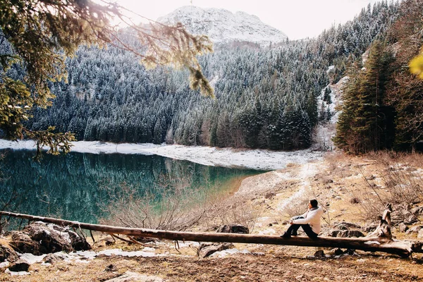 Žena relaxovat v zimním lese s výhledem na jezero a hory ve sněhu — Stock fotografie
