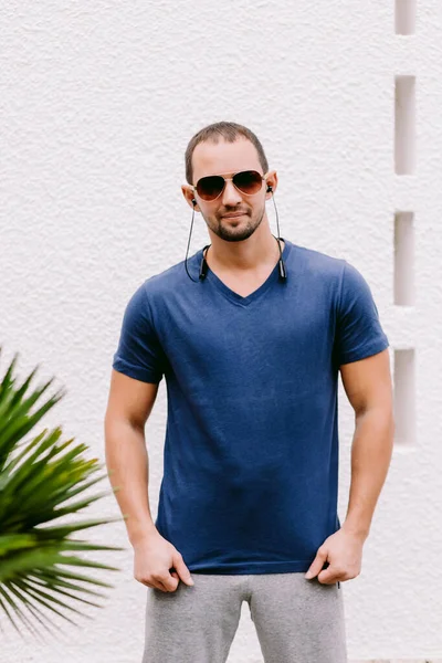 Mann in blauer T-Shirt-Attrappe trägt Sonnenbrille und hört Musik — Stockfoto