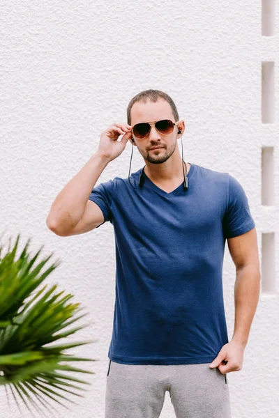 Man i blå t-shirt mockup bär solglasögon och lyssna musik — Stockfoto