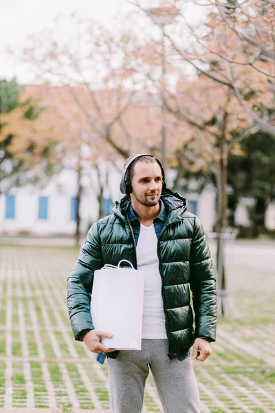 Beyaz kağıt çanta ve beyaz tişört modeli tutan bir adam. — Stok fotoğraf