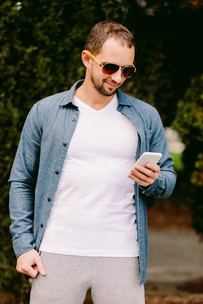 Pria mengenakan kaos putih memegang mockup telepon — Stok Foto