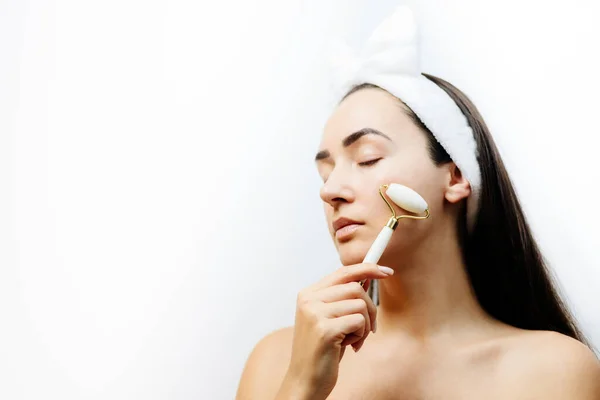 Mujer usando rodillo facial para masaje facial —  Fotos de Stock