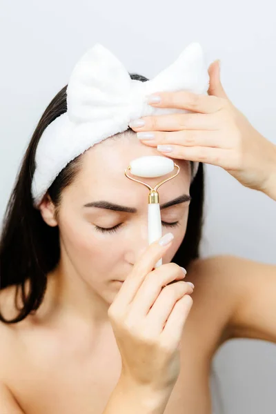 Mujer usando rodillo facial para masaje facial —  Fotos de Stock