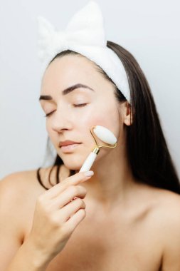 Yüz masajı için Yeşim Yüz Tekerleği kullanan Kadın