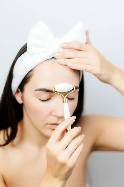 Retrato de mujer usando rodillo facial para masaje facial cuidado de la piel —  Fotos de Stock