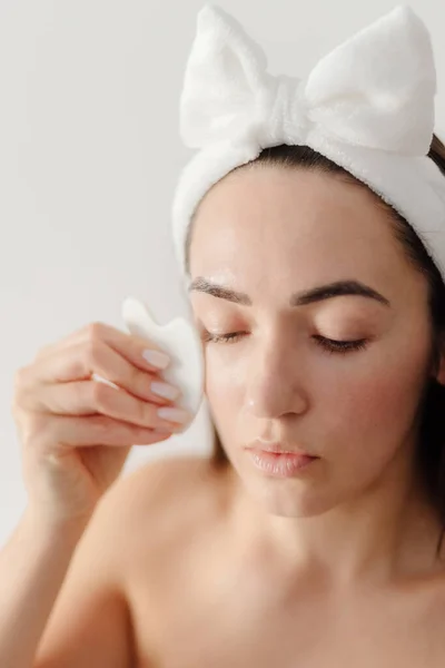 Woman using Gua Sha scraper over skin Stock Photo