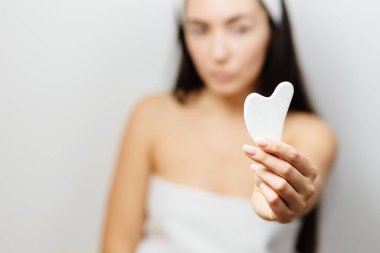 Gua Sha kazıyıcısı kullanan bir kadın.